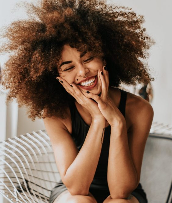 Image of a young, gleeful woman with long curly hair.